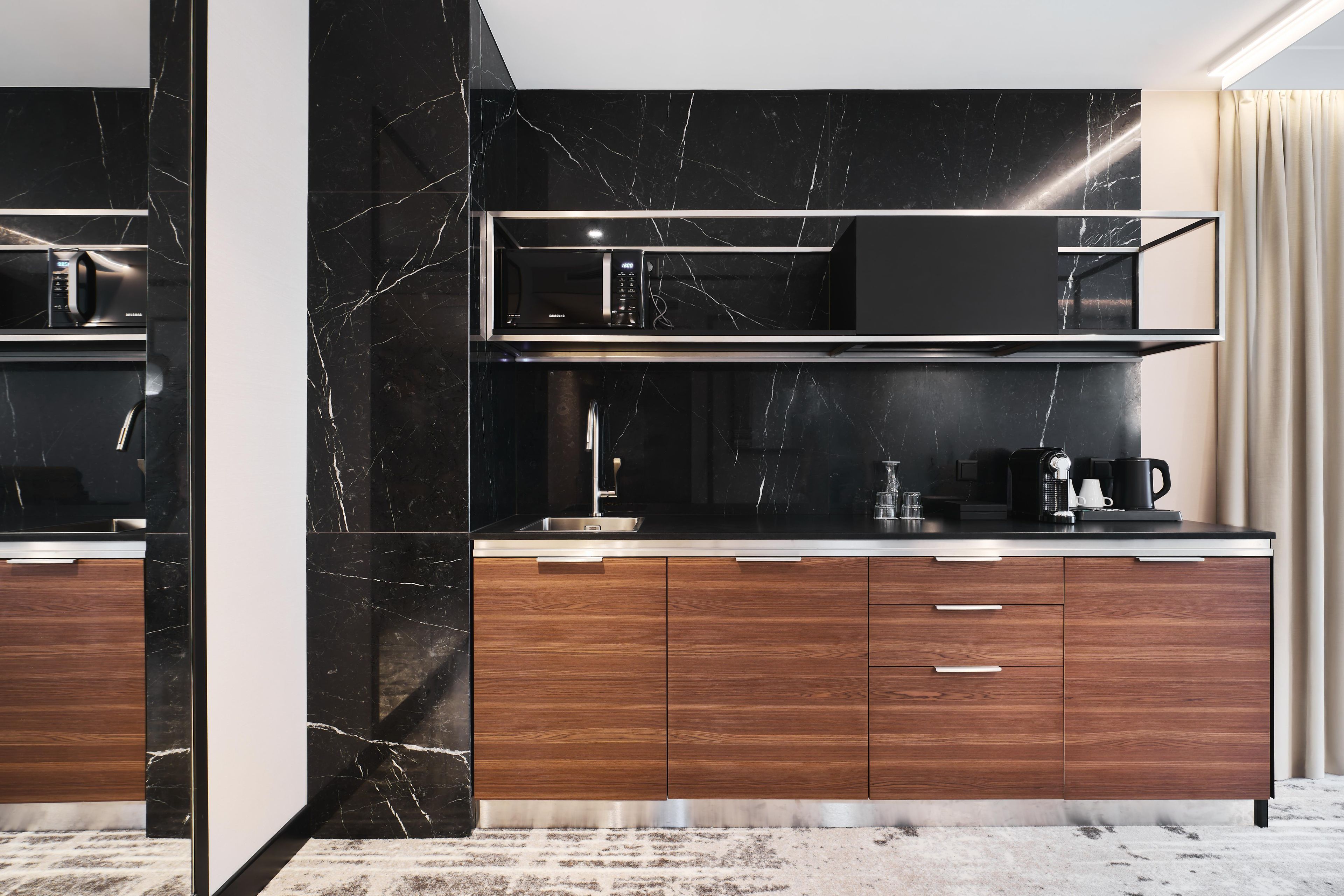 A modern kitchen with a black marble backsplash, stainless steel appliances, and wooden cabinets.