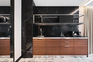 Una cocina moderna con salpicadero de mármol negro, electrodomésticos de acero inoxidable y armarios de madera.