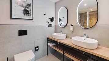 Un baño moderno con dos lavamanos, un inodoro y un espejo grande.