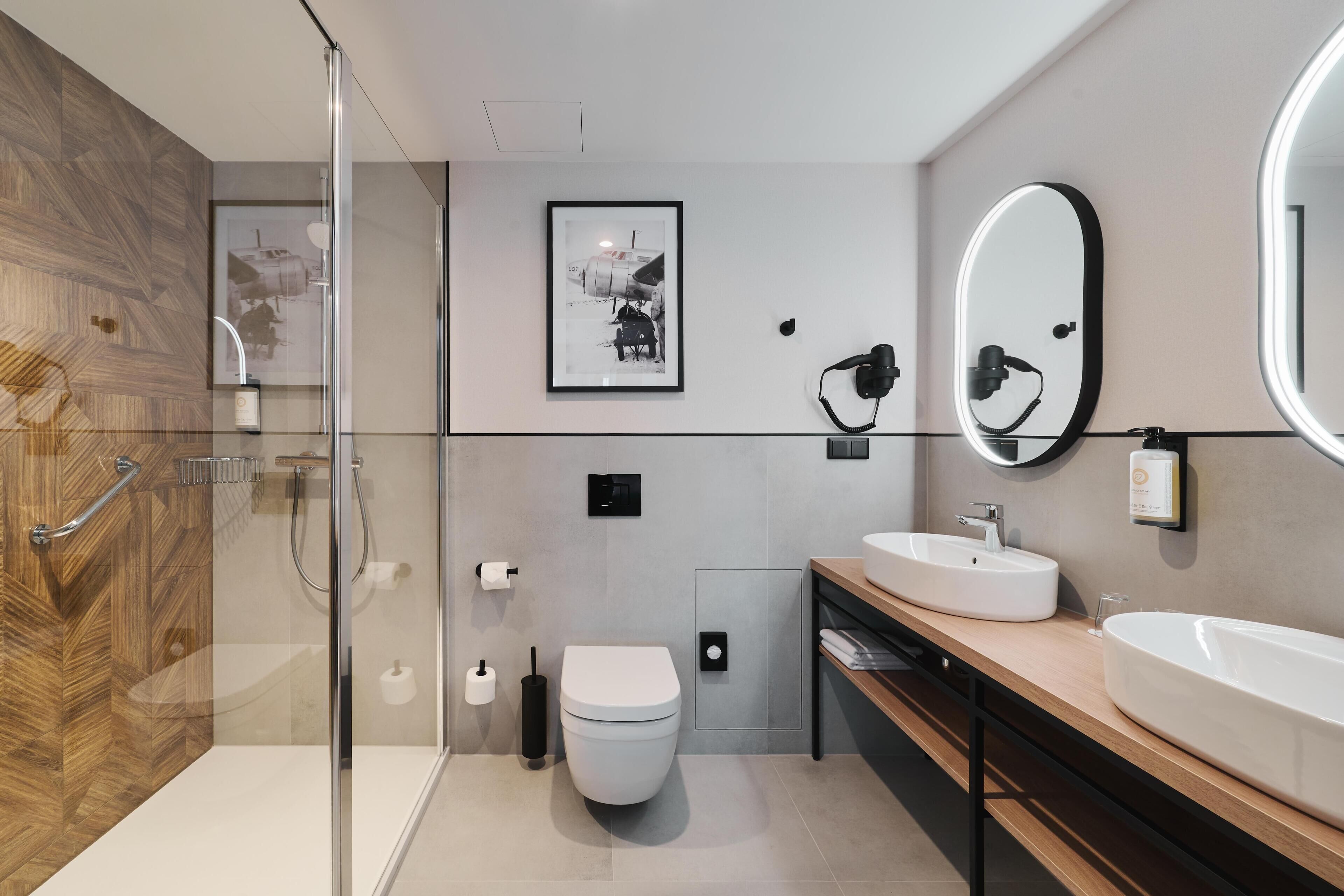 A modern bathroom with a glass shower enclosure, a wooden vanity, a large mirror, and a toilet.