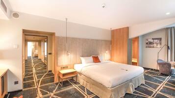 A hotel room with a bed, a desk, a chair, a lamp, and a picture on the wall.