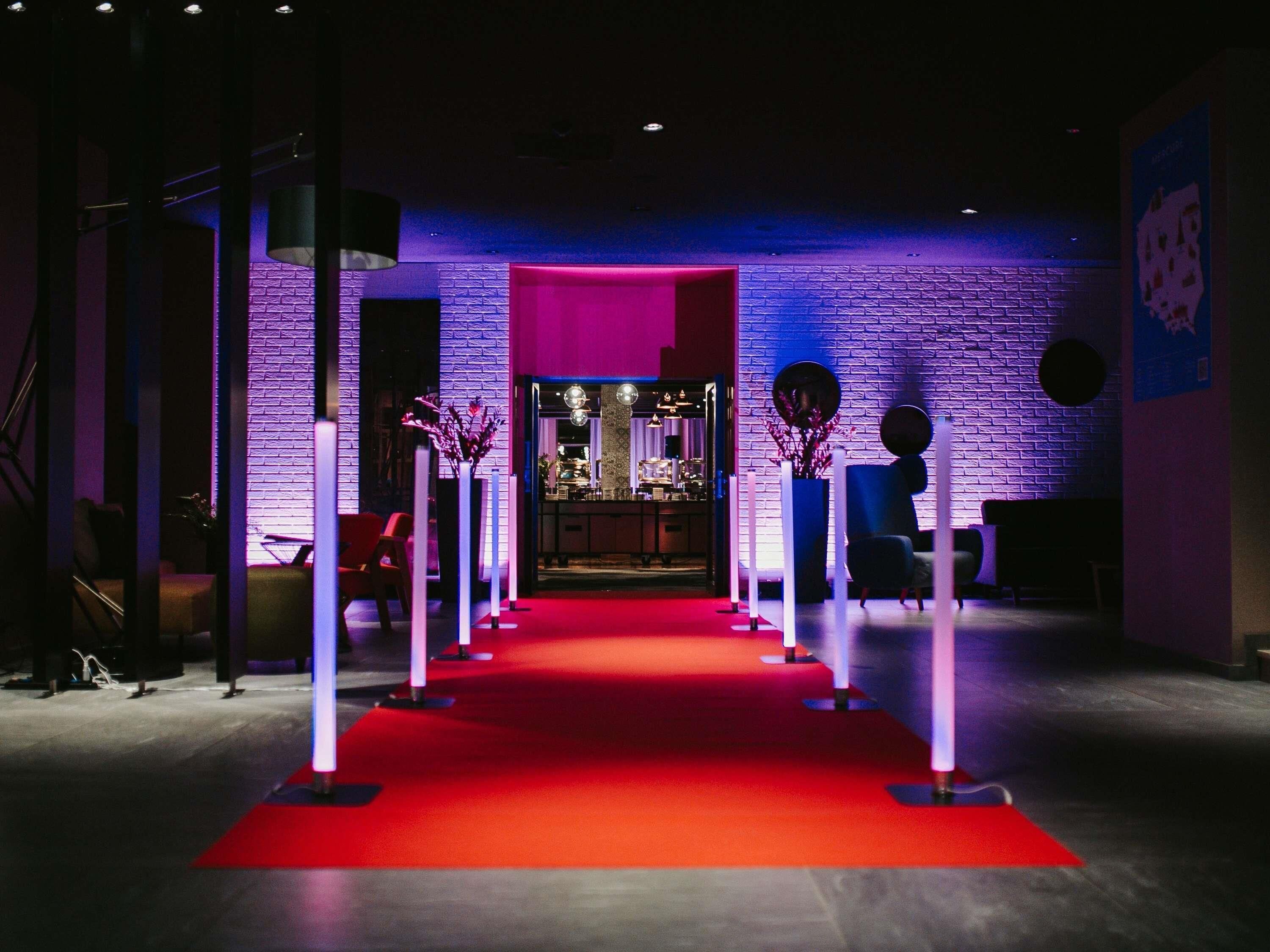 A red carpet leading to a bar area with a brick wall backdrop and modern decor.