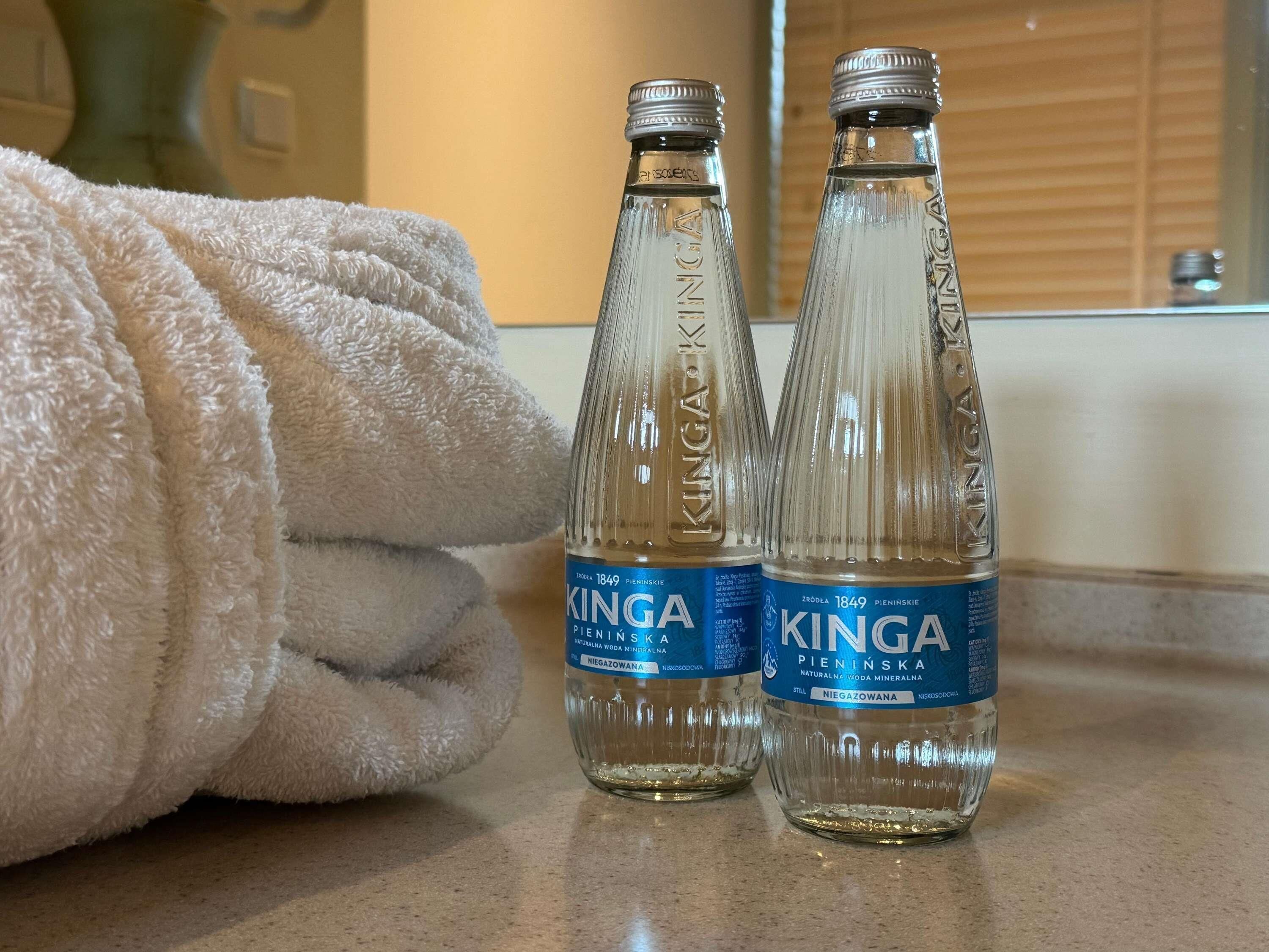 Zwei Flaschen Kinga Wasser auf einer Arbeitsplatte mit einem gefalteten Handtuch.