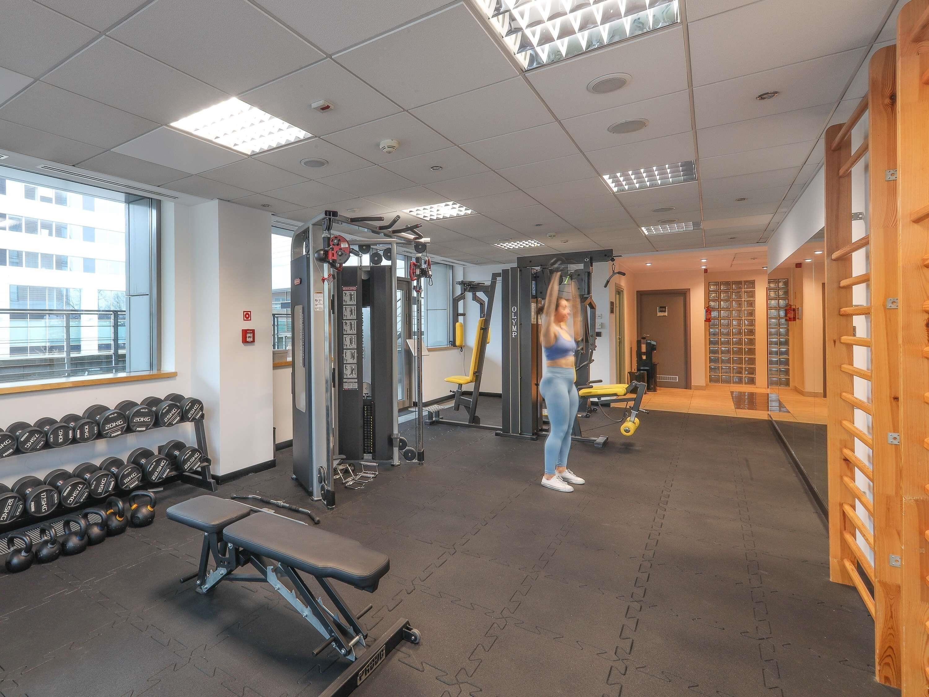 Une salle de sport équipée de matériel de musculation, d’haltères et d’un banc.