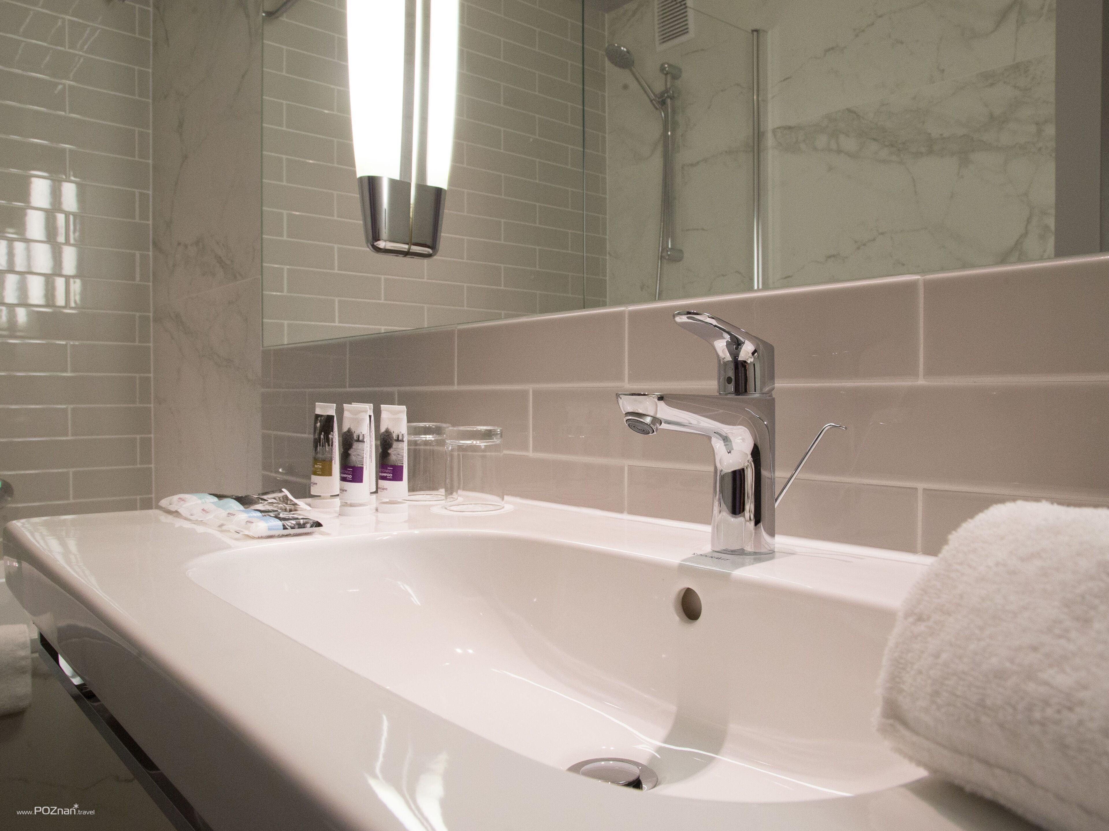 Un baño moderno con un lavabo blanco grande, accesorios de cromo y cabina de ducha de vidrio.