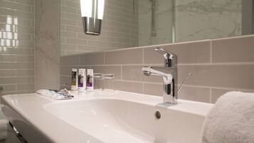 Un baño moderno con un lavabo blanco grande, accesorios de cromo y cabina de ducha de vidrio.