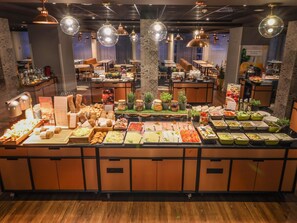 A buffet area with various food options, tables, and hanging lights.