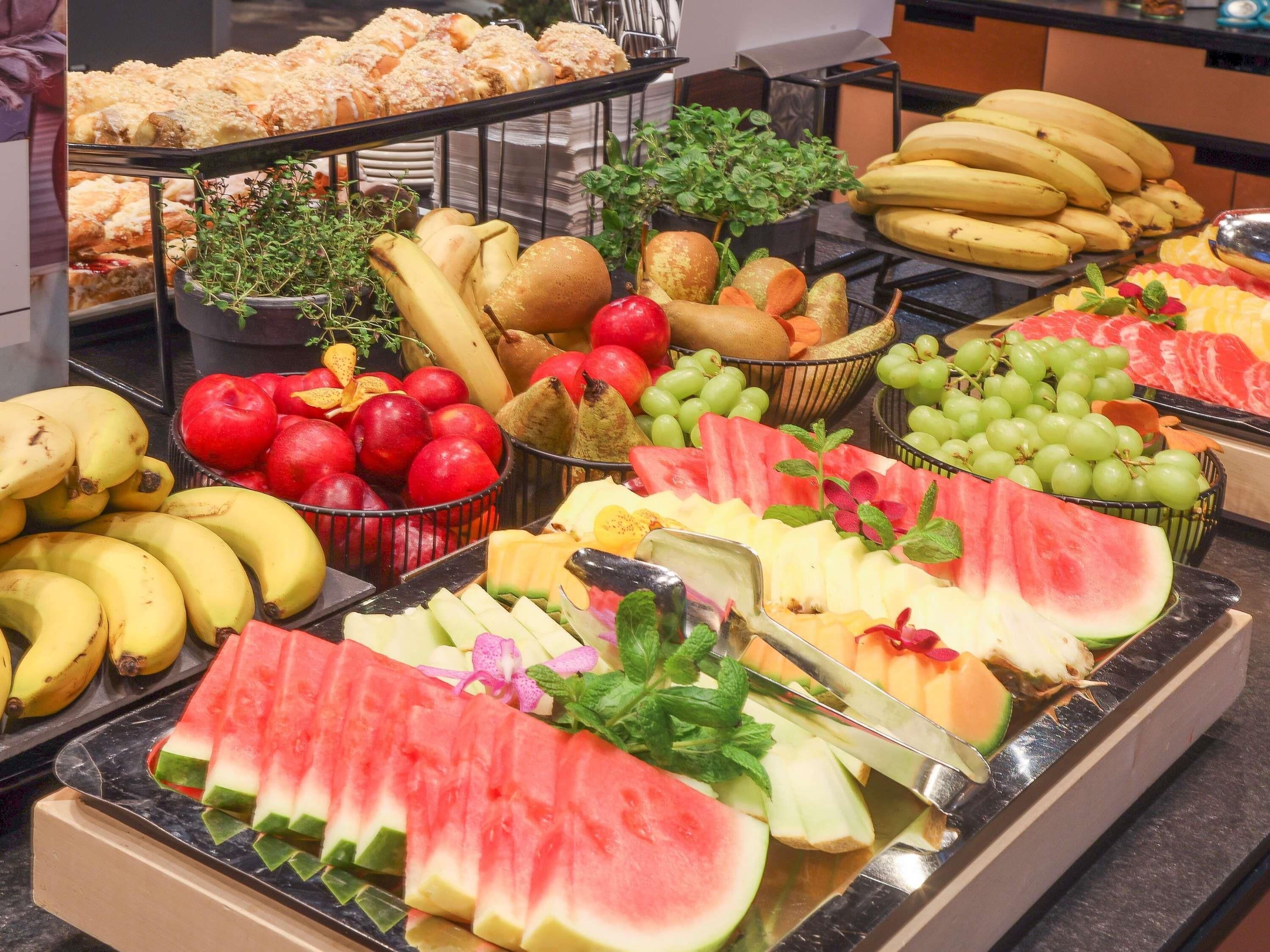 Un bufé con diversas frutas y pasteles.