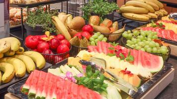 Un bufé con diversas frutas y pasteles.