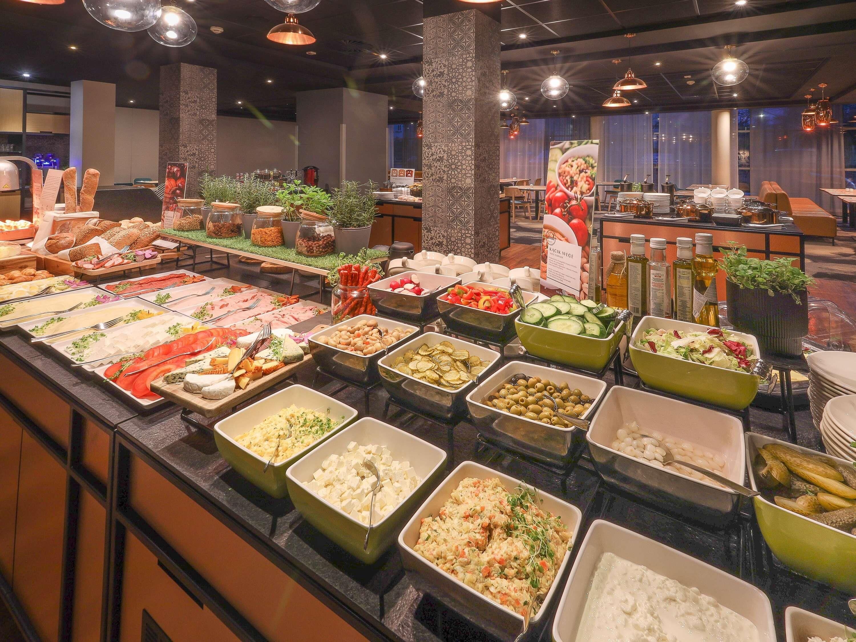 A buffet with various food items and a seating area with tables and chairs.