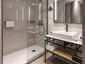 A modern bathroom with a glass-enclosed shower, a white sink, and a mirror above it.