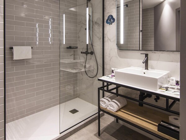 A modern bathroom with a glass-enclosed shower, a white sink, and a mirror above it. - Hotel Mercure Poznan Centrum (Poznan)