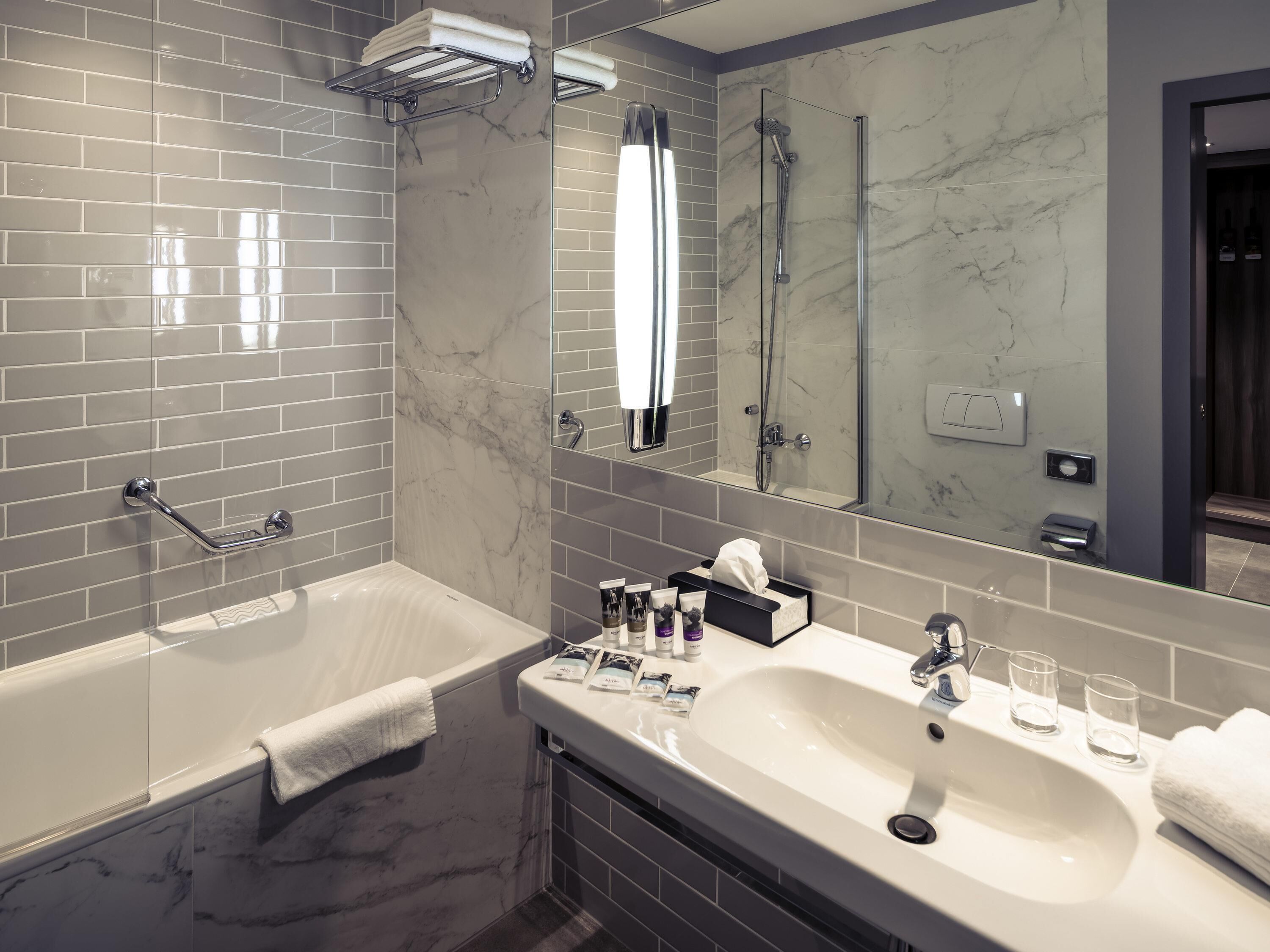 A modern bathroom with a bathtub, a large mirror, a vanity with a sink, and a shower area.