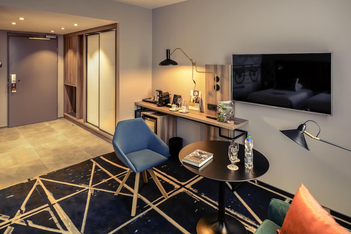 Une chambre d’hôtel équipée d’un bureau, d’une chaise, d’une télévision et d’un tapis à motifs.