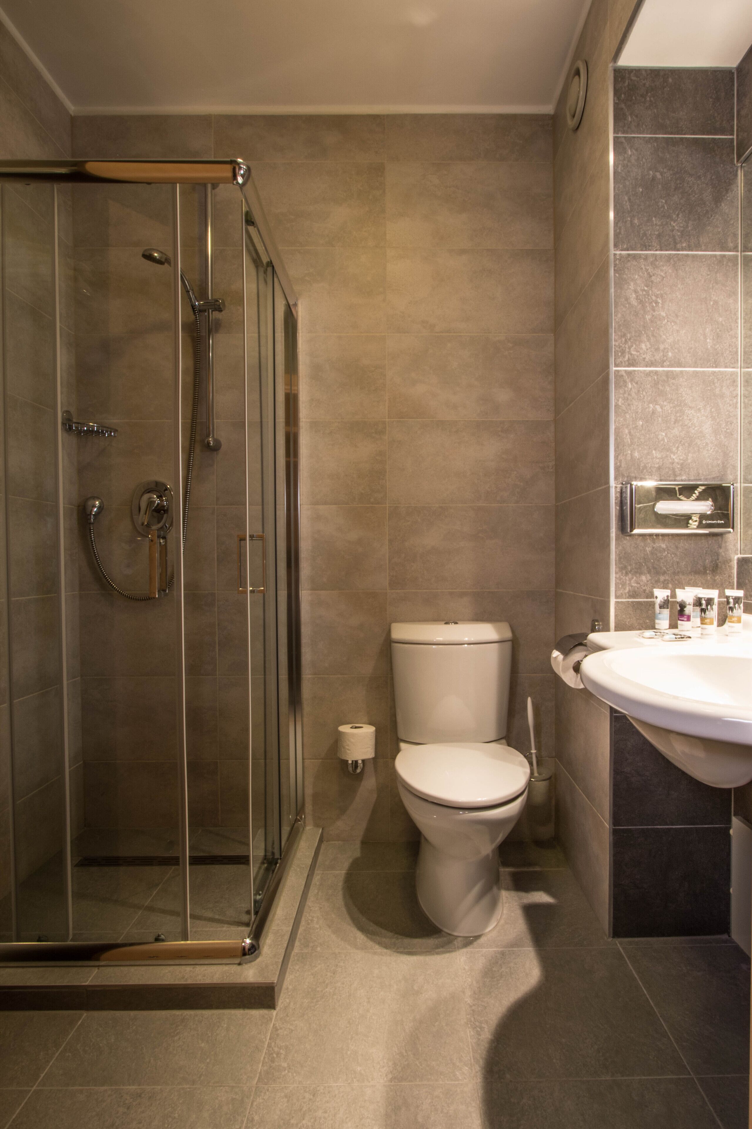 Un baño con ducha de vidrio, inodoro y lavamanos.