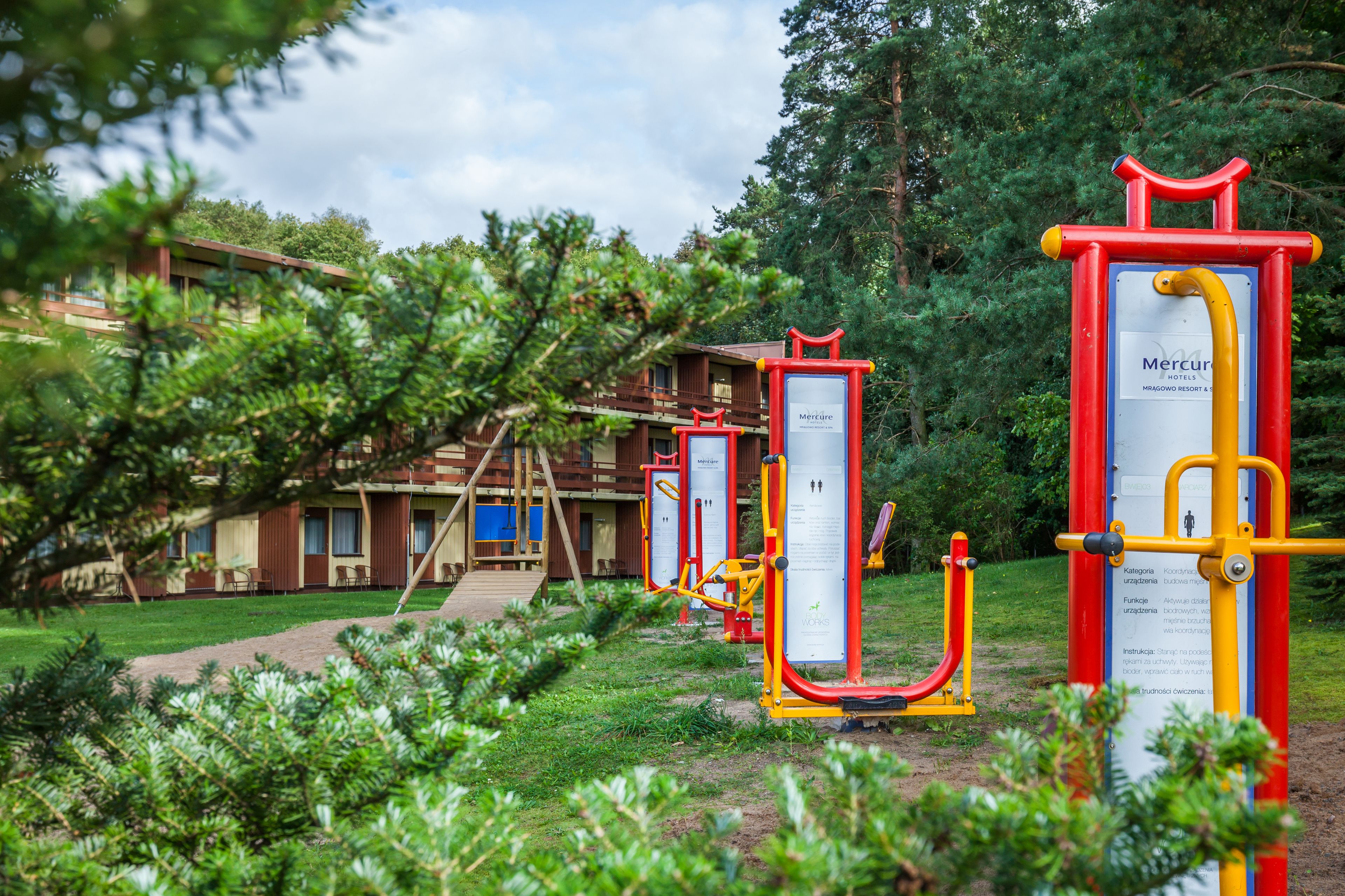 Equipos de ejercicio al aire libre, un edificio con fachada de madera y un cartel del hotel Mercure.