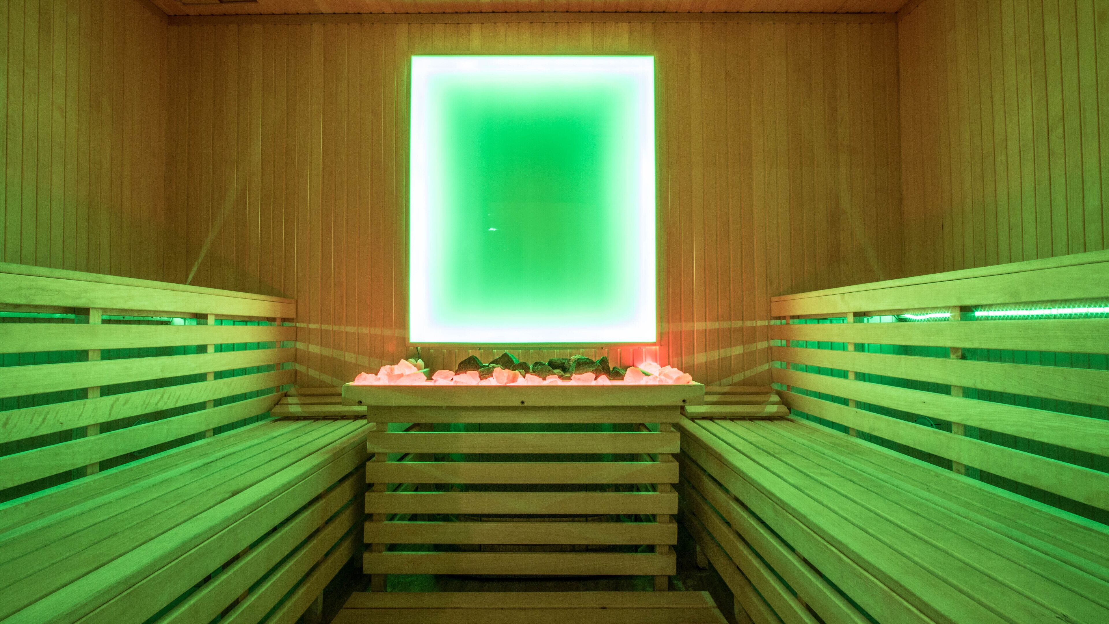 A sauna with wooden benches and a central heated floor.