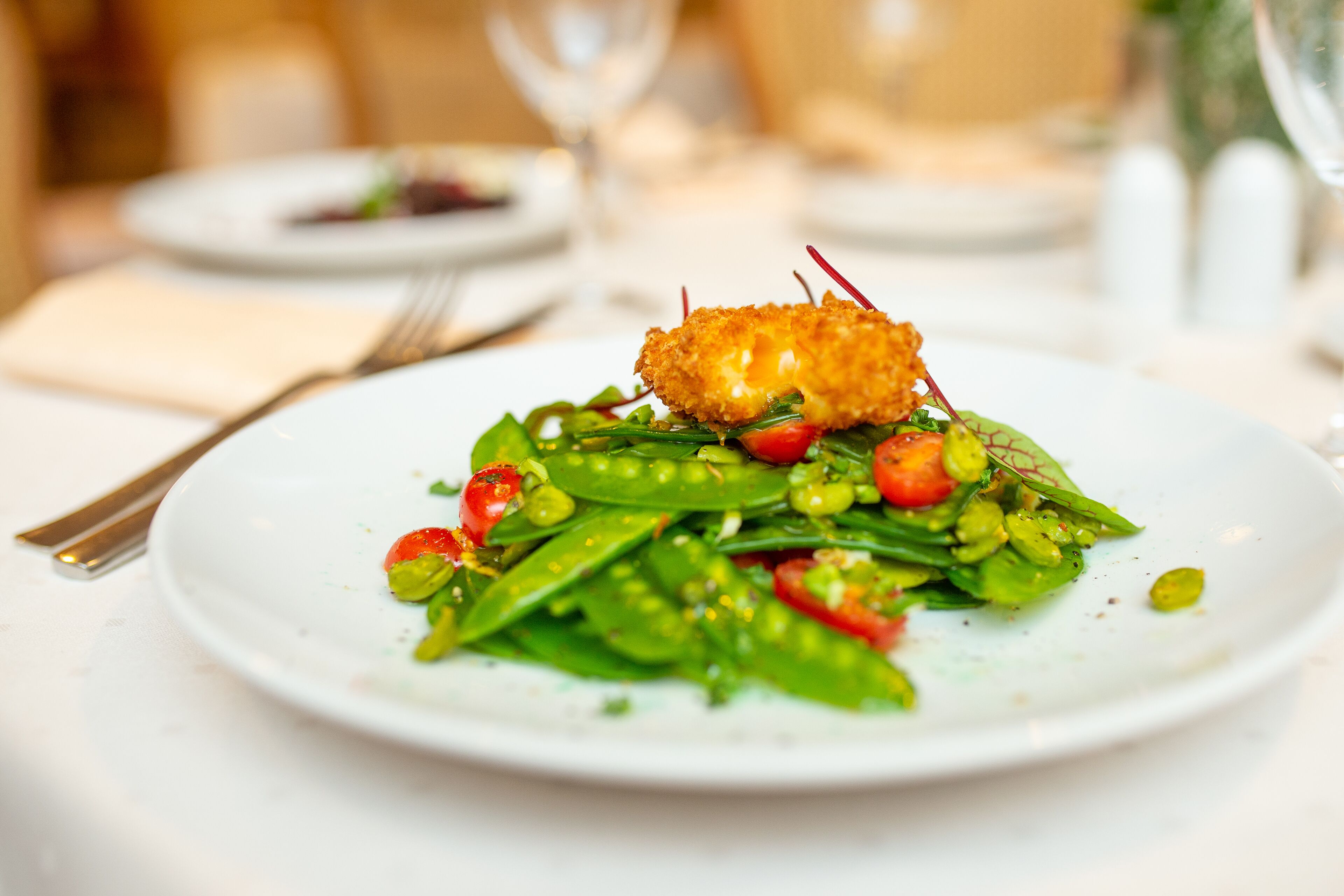 A plate of food with a crispy topping and a variety of vegetables.