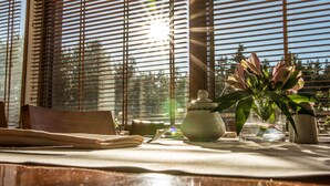 Una mesa con una tetera, un florero con flores y una silla de madera.