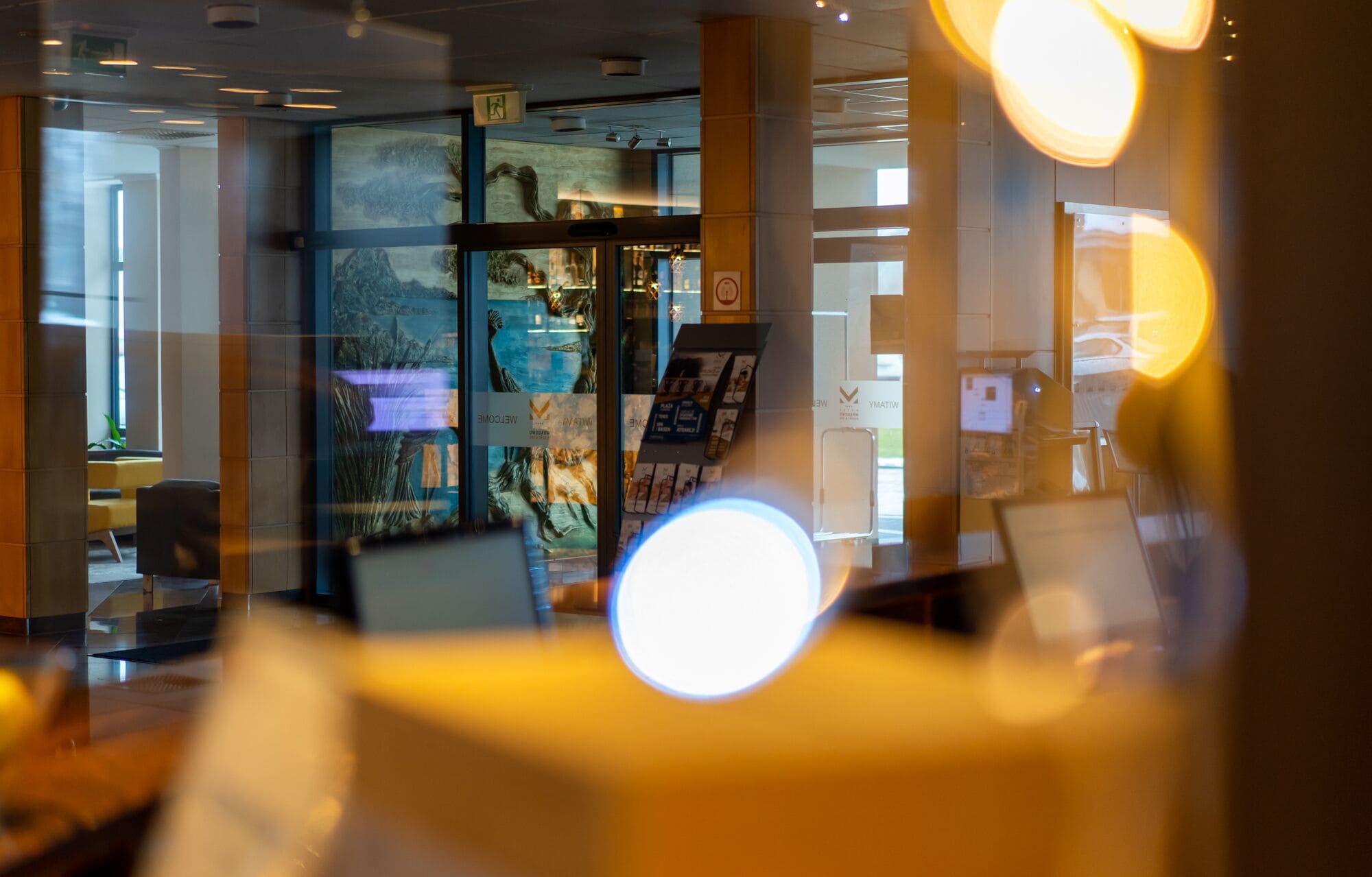 Et moderne interiør med glasvægge, en receptionsdisk og et tydeligt skilt med 'Welcome'.