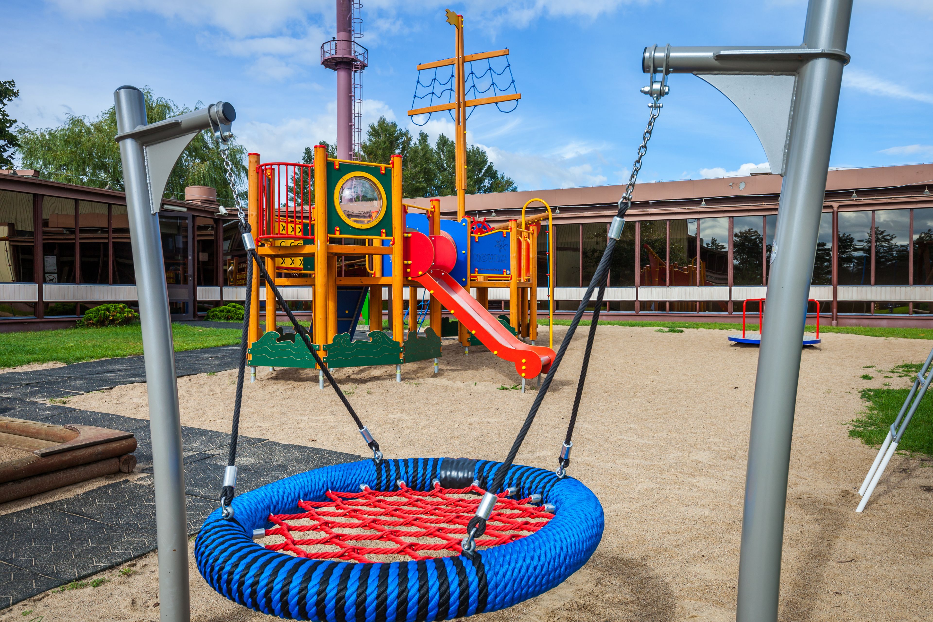 A playground with a swing set, a slide, and a climbing structure.