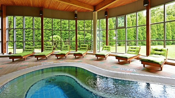 Zona de piscina con sillones de descanso y vistas al exterior.