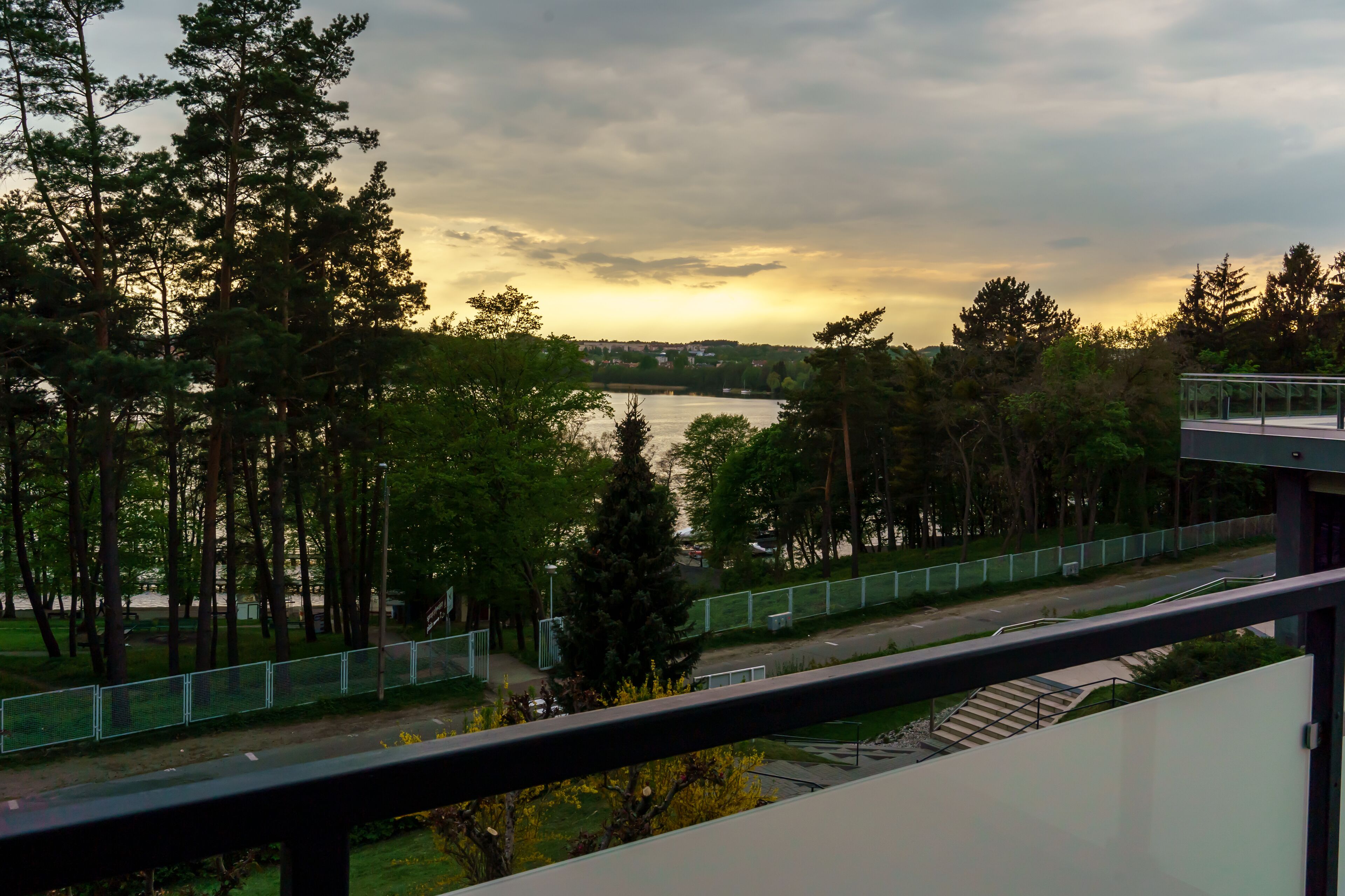 A view from a balcony overlooking a river, surrounded by trees and a bridge.