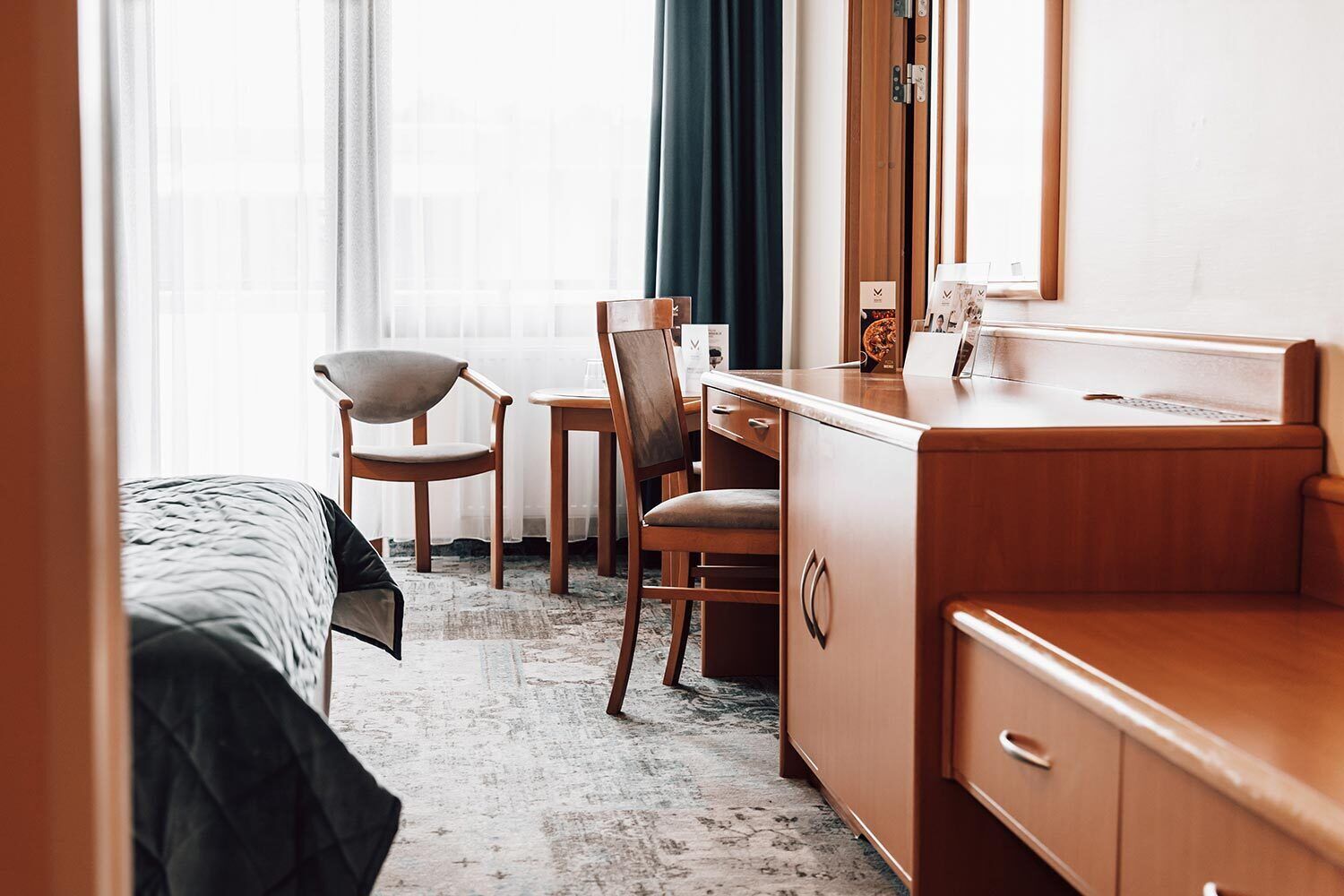 Une chambre d’hôtel comprenant un lit, un bureau, une chaise et une coiffeuse avec un miroir.