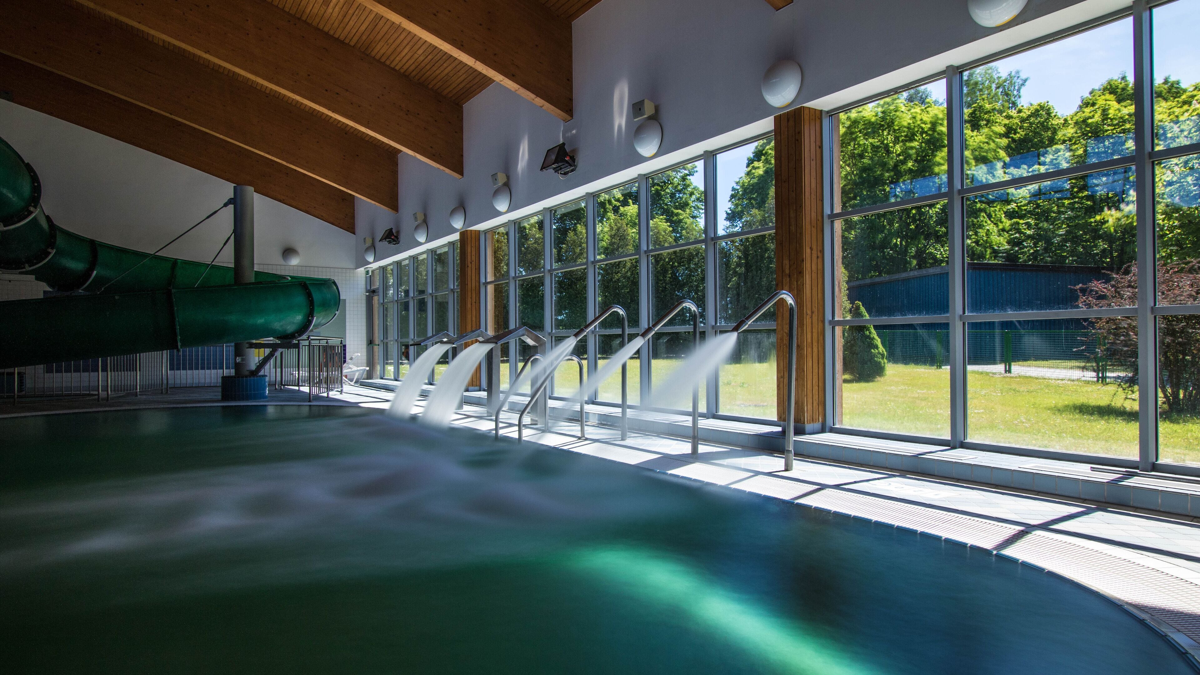 Una piscina con tobogán, ventanas amplias y vistas al exterior.