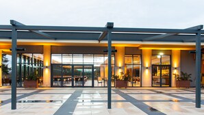 Una entrada de edificio moderna con un vestíbulo cubierto, puertas de cristal y zona de estar al aire libre.