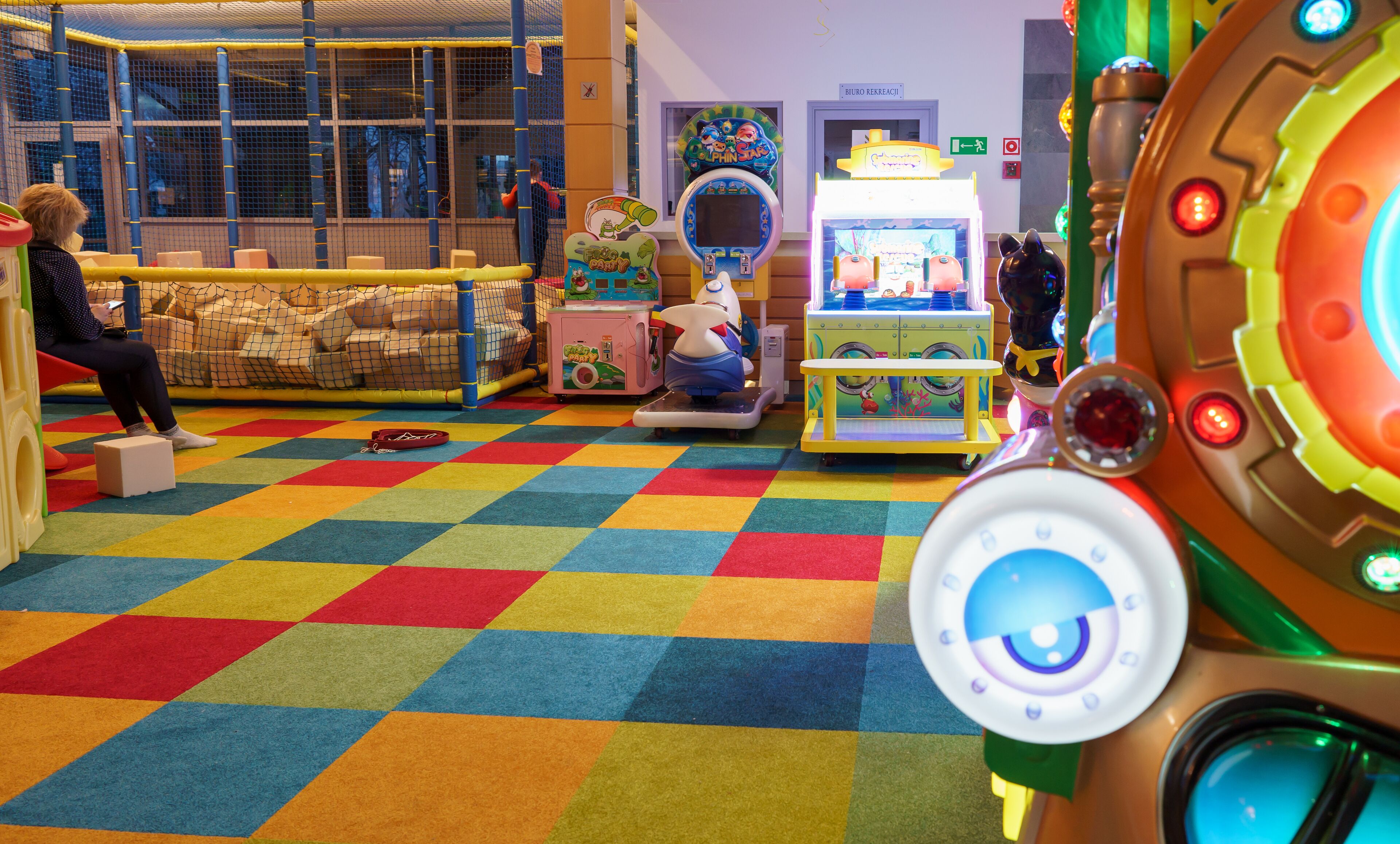 Un área de juegos colorida con distintos juegos y un niño jugando.