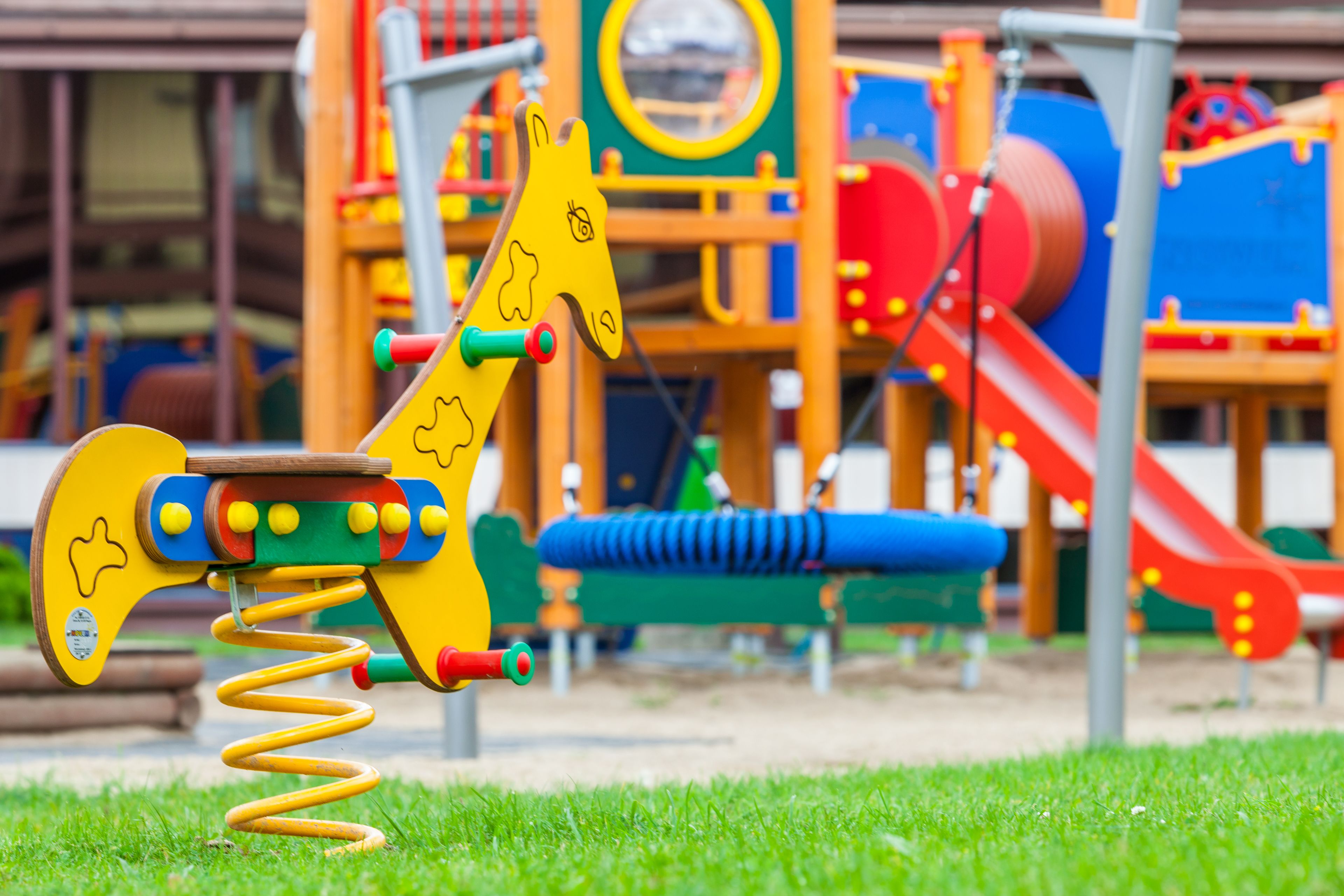 A playground with a giraffe-shaped swing set and a slide.
