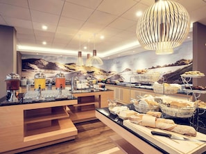 Ein reichhaltiges Buffet mit verschiedenen Speisen, eine große dekorative Leuchte und ein aussichtsreicher Wandgemälde.