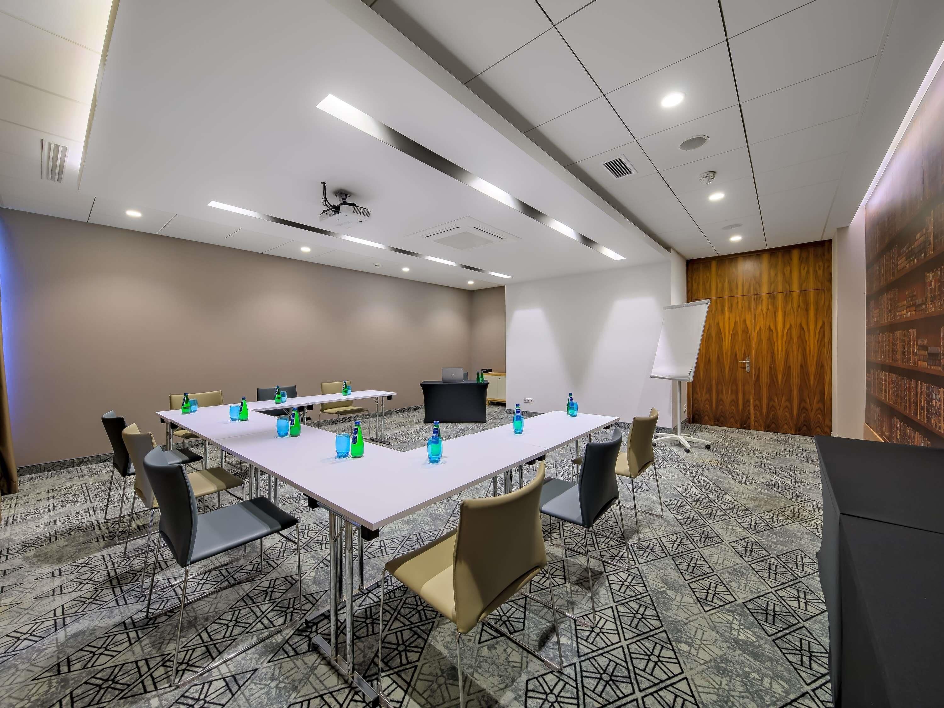 A conference room with a long table, chairs, a whiteboard, and a projector.
