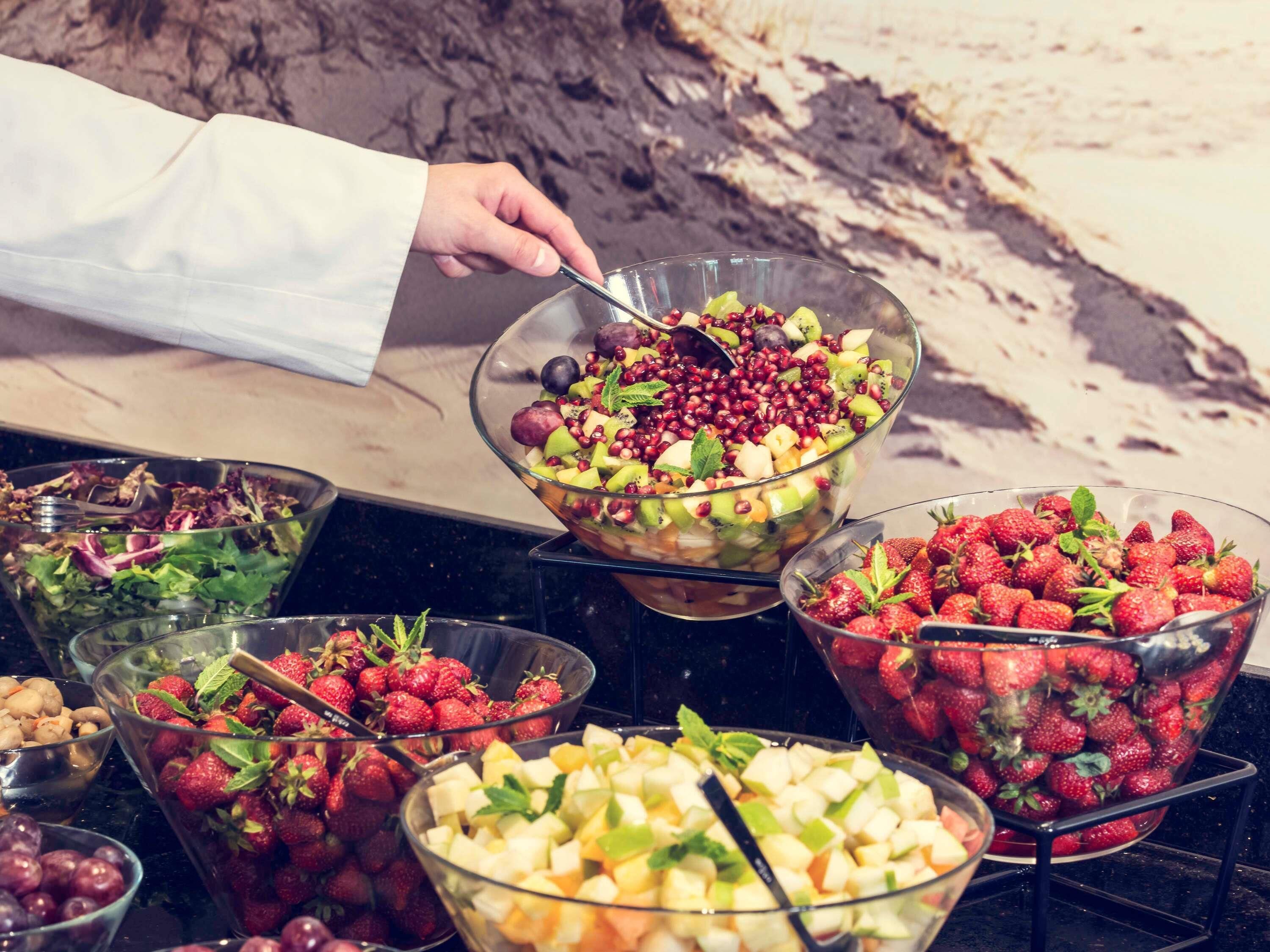 Un bufé con diversas opciones de fruta y ensaladas.
