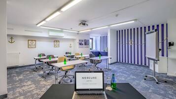 A conference room with tables, chairs, a laptop, and a projector.