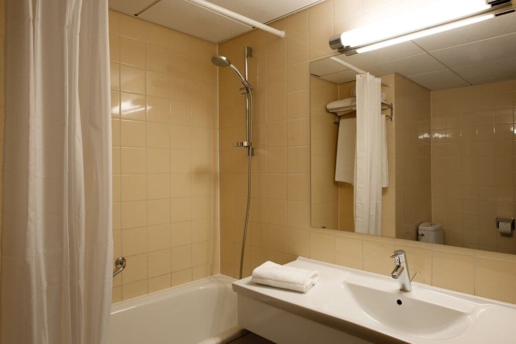 A bathroom with a bathtub, a sink, a mirror, and a shower.