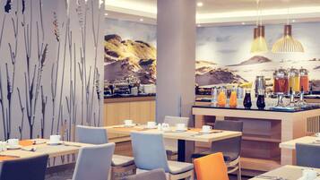 A modern hotel dining area with a buffet setup, seating arrangements, and a decorative wall with abstract art.