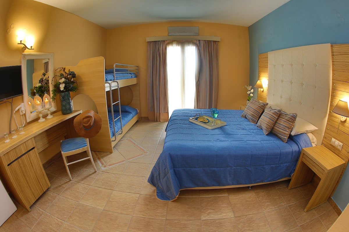 A bedroom with a bunk bed, a desk with a mirror, and a bedside table with a lamp.