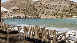 Una terraza con mobiliario blanco a rayas y vistas a una montaña y al agua.
