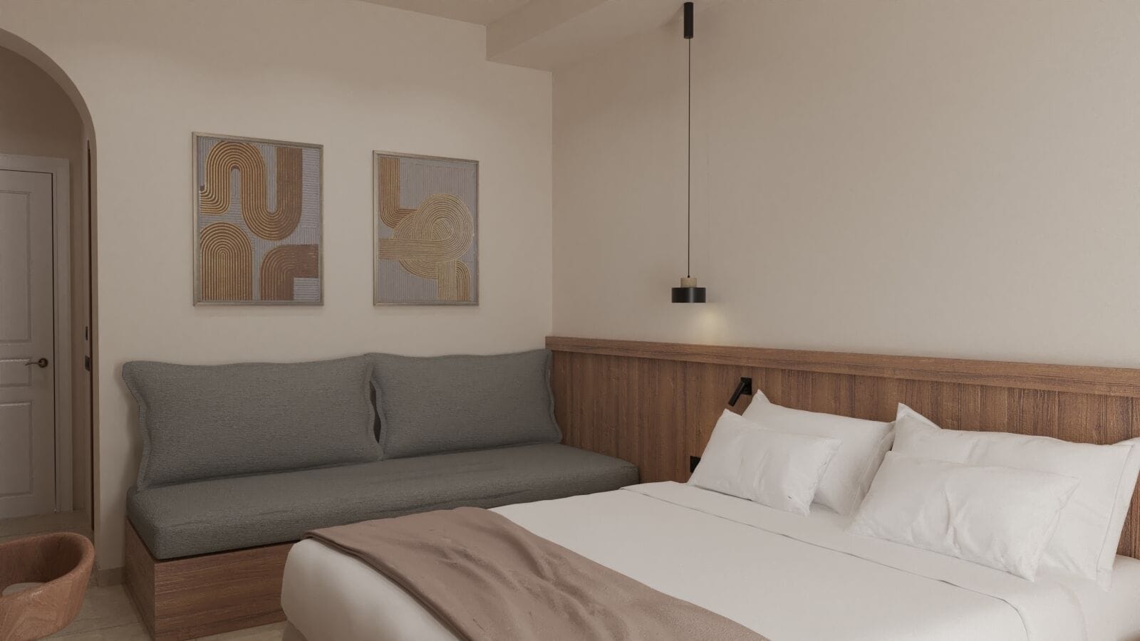 A bedroom with a bed, a grey sofa, and two wall art pieces.