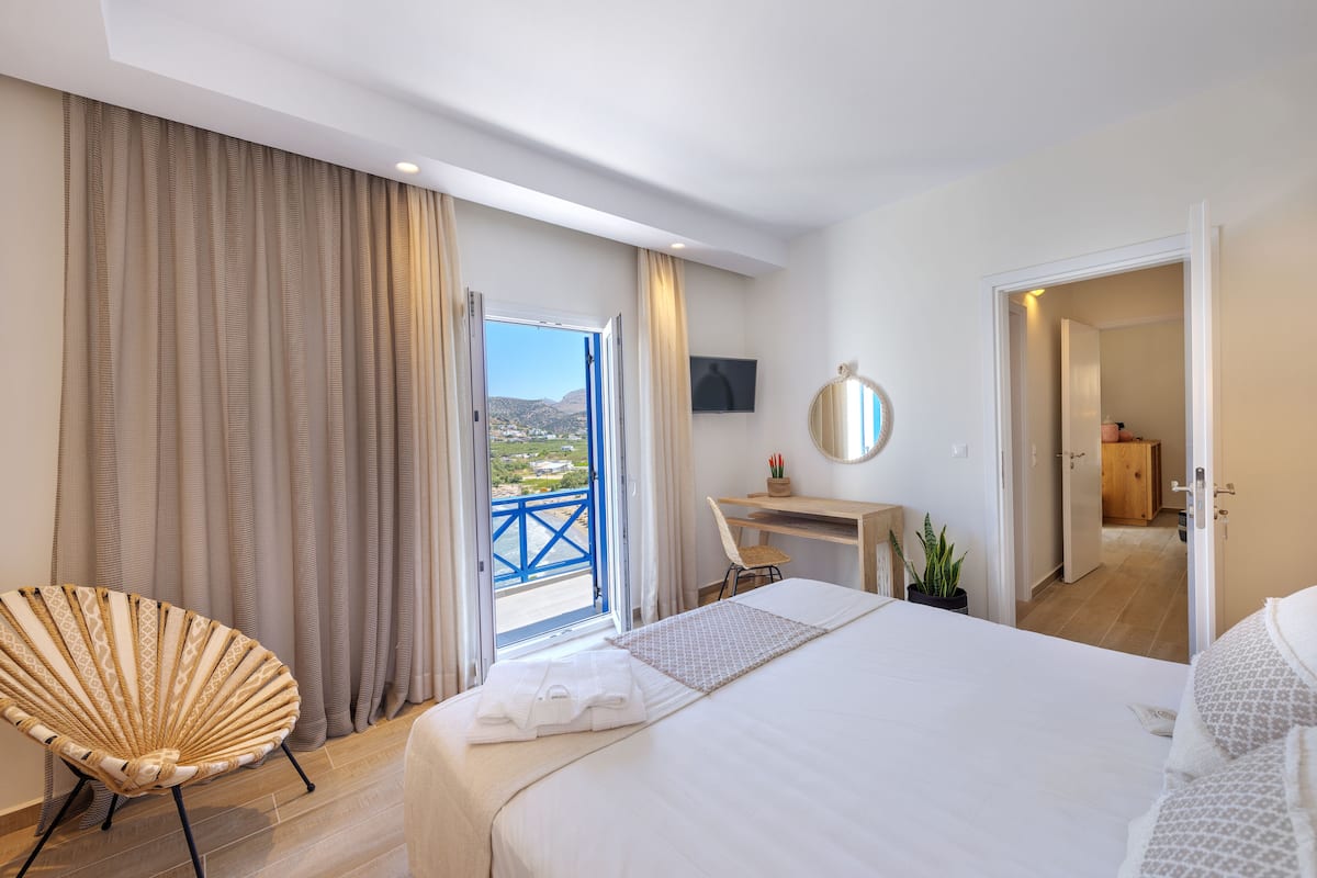 A hotel room with a bed, a chair, a desk, and a view of the outdoors.
