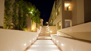 Una escalera bien iluminada que conduce a un edificio de diseño moderno, rodeado de vegetación.