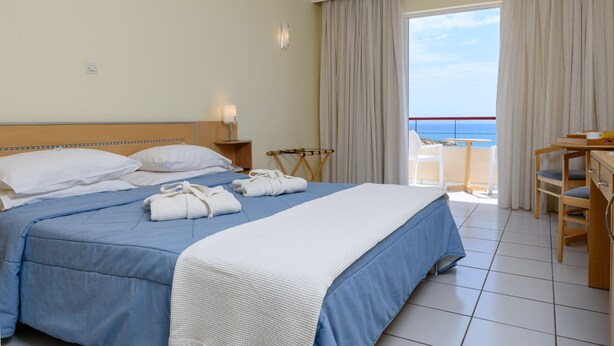 Una habitación de hotel con cama, escritorio y vista al mar.