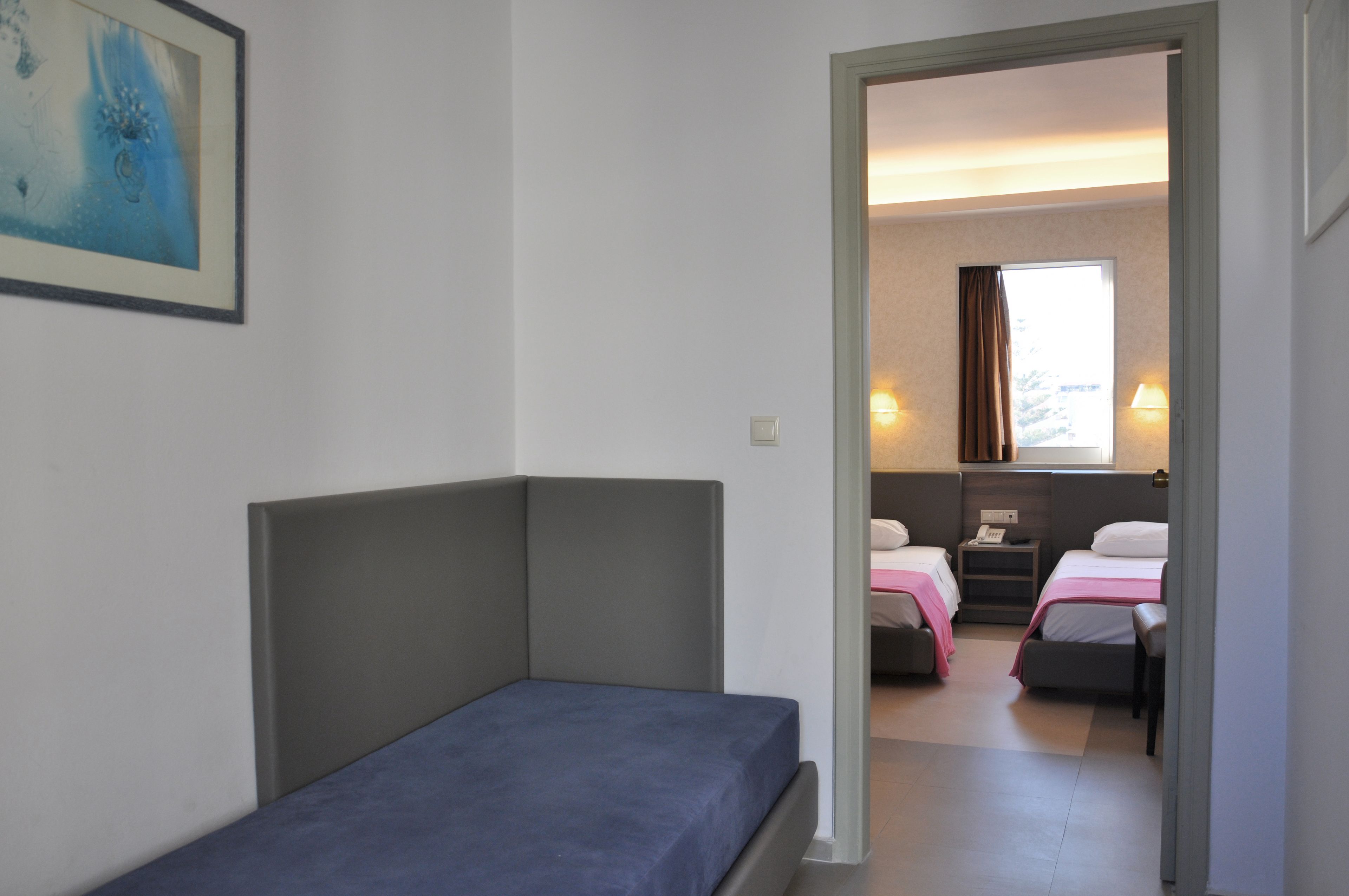 Una habitació amb un llit individual, un escriptori petit i una finestra amb cortines.