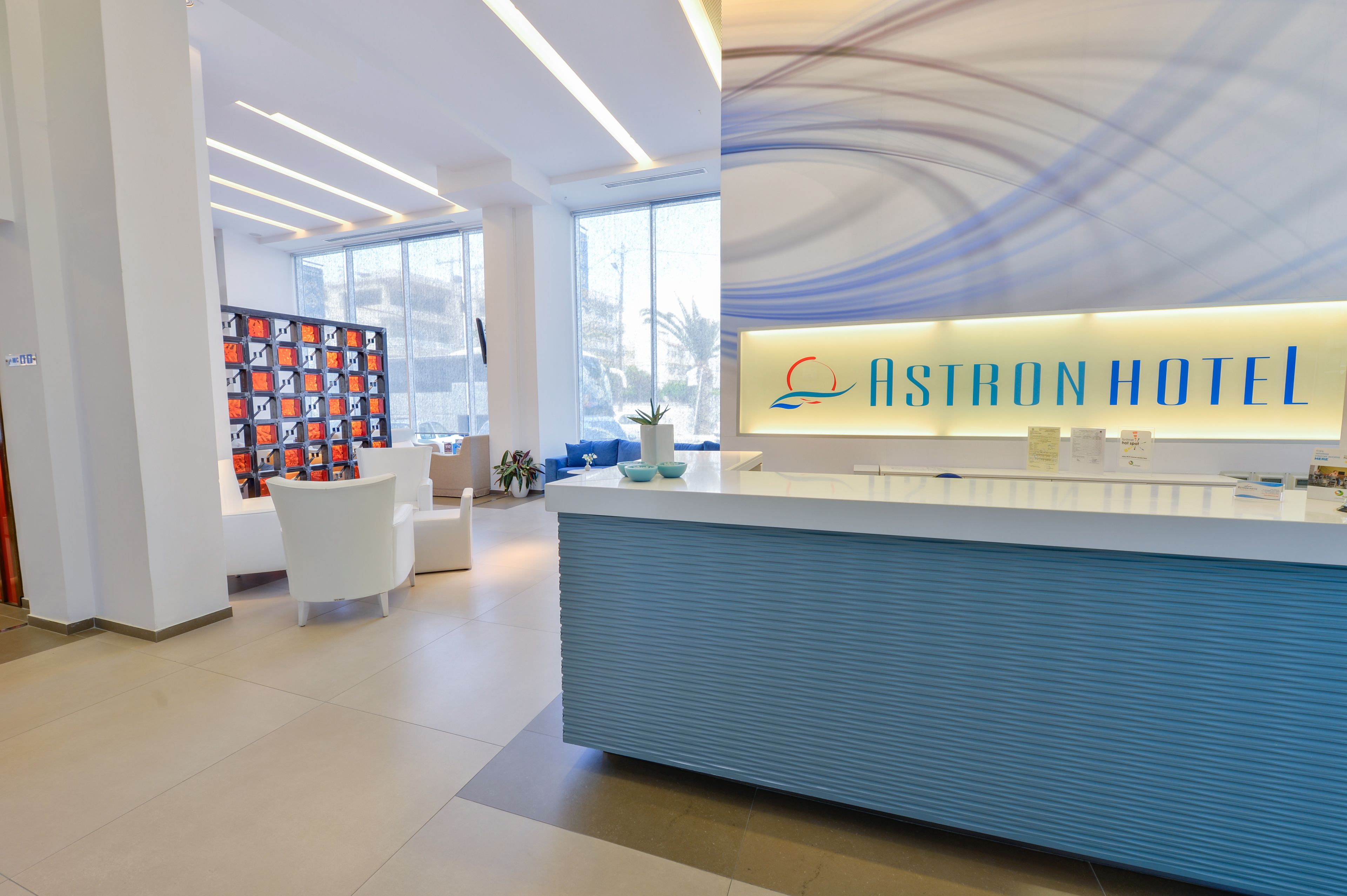 A modern hotel reception area with a blue counter, a large window, and a wall with framed pictures.