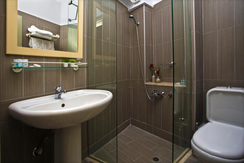 A modern bathroom with a glass-enclosed shower, a white sink, and a toilet.
