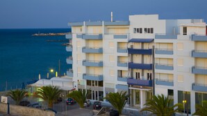 A multi-story hotel with balconies, a parking area, and a view of the sea. - Astron Hotel (Ierapetra)