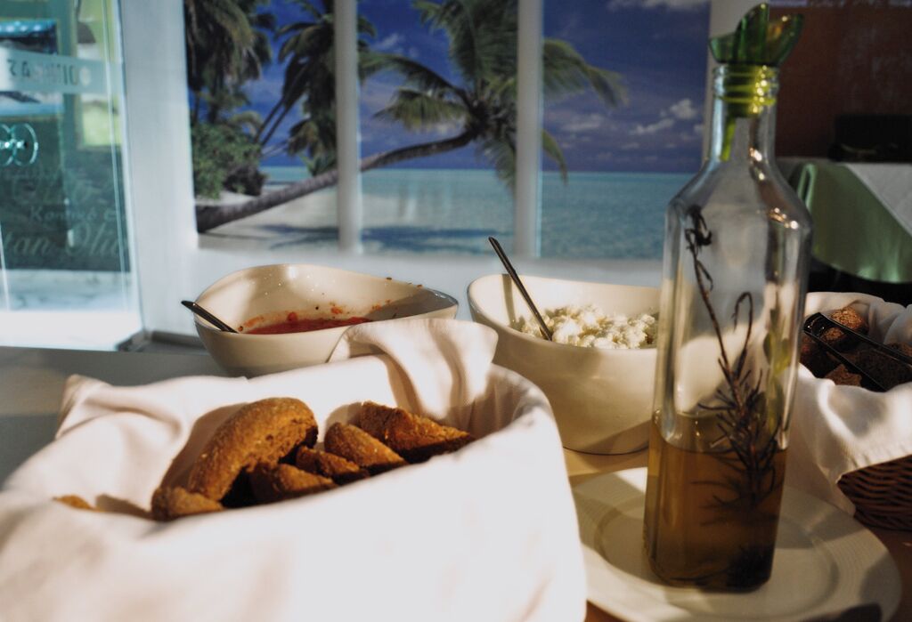 A dining table with a bowl of soup, a bowl of salad, and a bottle of olive oil.