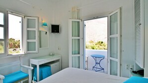 A room with a bed, a desk, a chair, and a small balcony with a table. - Spiros & Hiroko Hotel - Adults Only (Santorini)